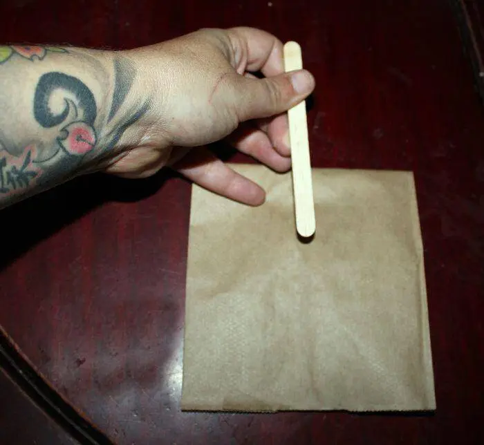 sticking popcicle stick to brown bag