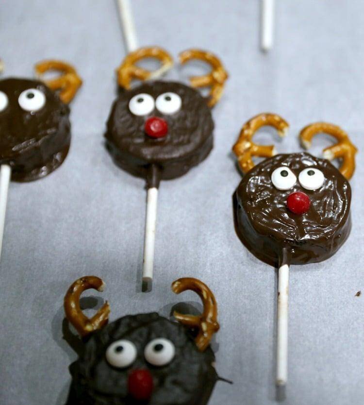 How to Make Reindeer Christmas Cookie Pops 16 reindeer cookie pops laying on wax paper