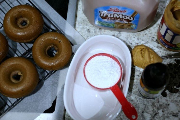 Baked Chocolate Chip Cake Donuts with Peanut Butter Glaze 15 powder sugar in measuring cup, peanut butter on spoon on counter