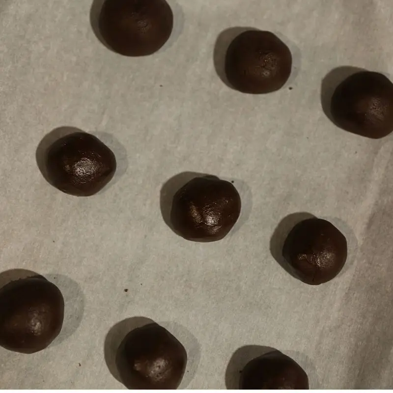 brownie cookie dough rolled into balls on parchment paper