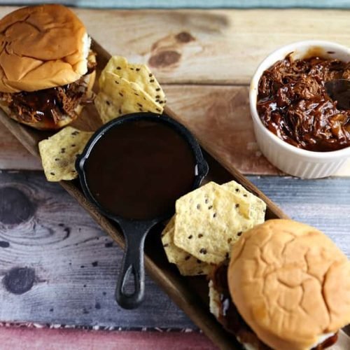 bbq sandwiches on plate with bbq sauce and chips