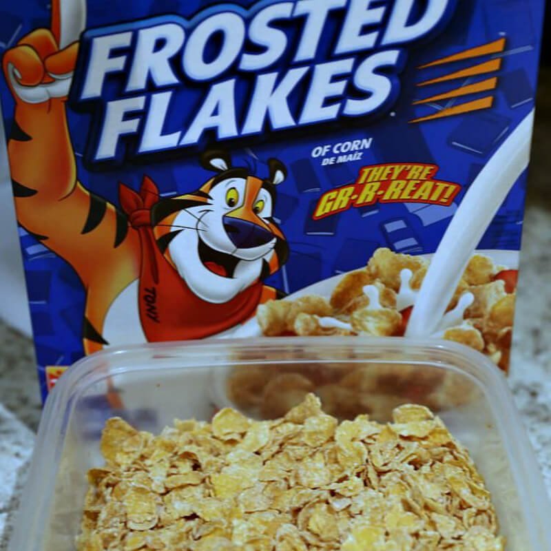 No Bake Peanut Butter Cereal Bars 11 frosted flakes in Tupperware bowl with cereal box in background