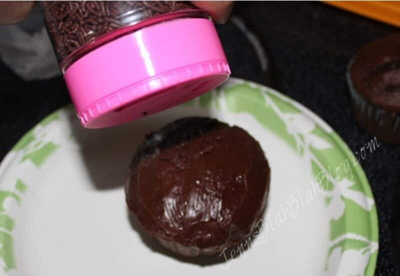 putting sprinkles on chocolate cupcake