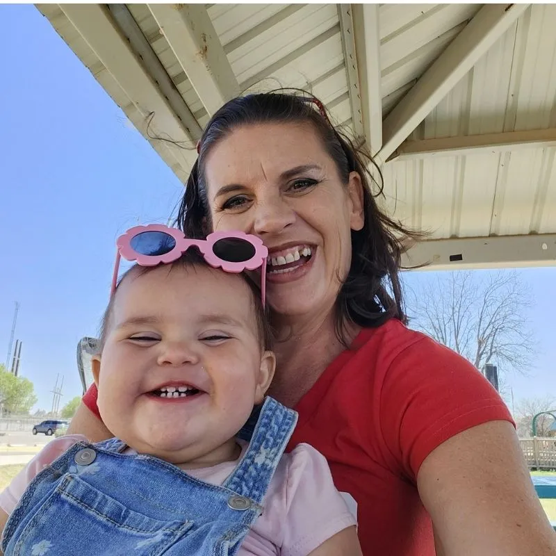 3 Secrets to How I Mentally Prepared to Quit Smoking 7 Jenn Brockman owner of Half Baked Media smiling with granddaughter on her lap wearing pink sunglasses on her head.