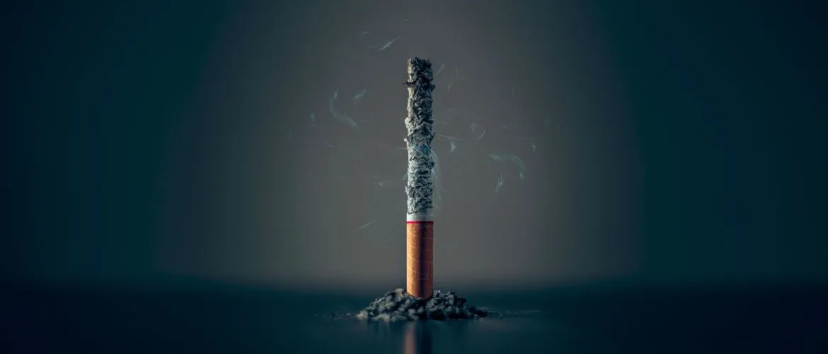 cigarette sitting on the table with the butt end down and the top ashes just sitting on the butt of the cigarette