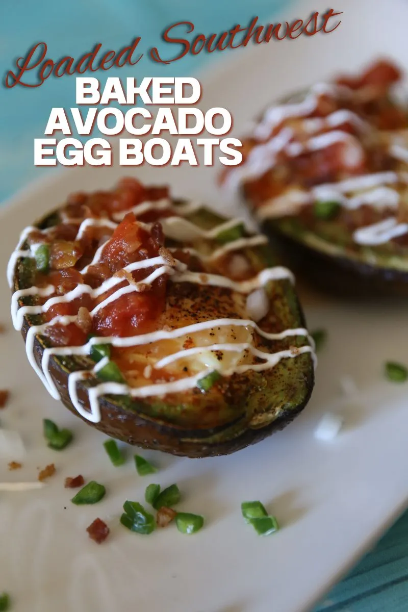 Loaded Southwest Baked Avocado Egg Boats topped with diced jalapeno onion and sour cream staged on a white plate