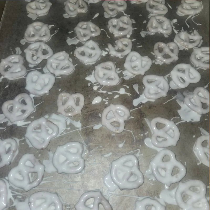 pretzels covered in almond bark laying on cookie sheet 