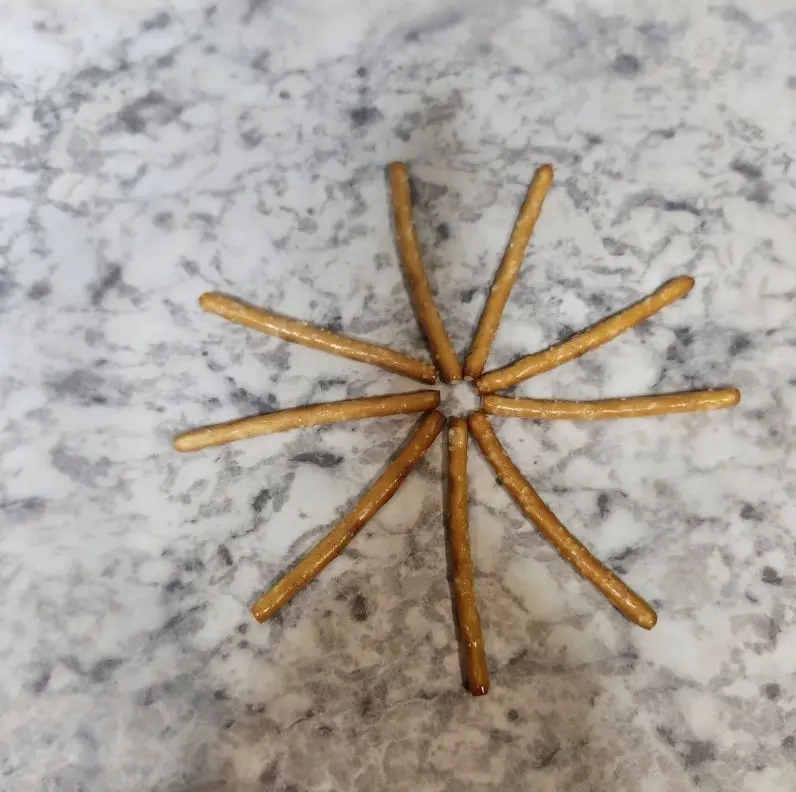 stick pretzels positioned in a star shape on a piece of wax paper.