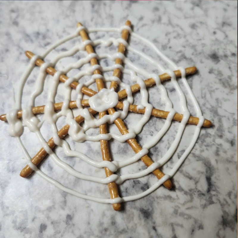 pretzel spider web freshly made sitting on a piece of wax paper to dry.