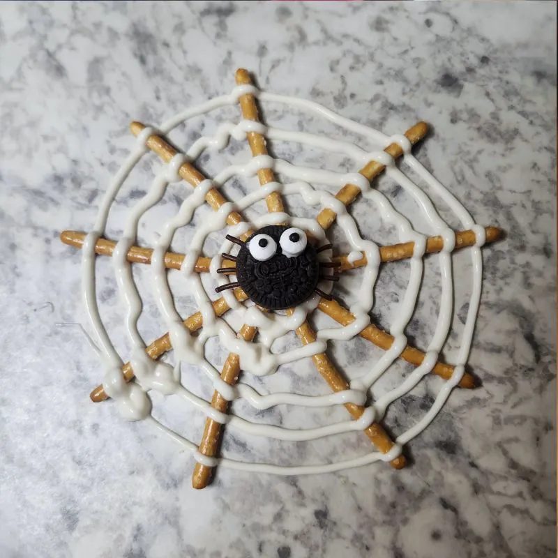 fully constructed oreo pretzel spider web drying on wax paper.