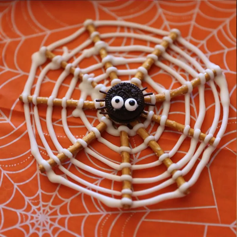 Oreo Pretzel Spider Web sitting on table with orange cloth with spider webs on it. 