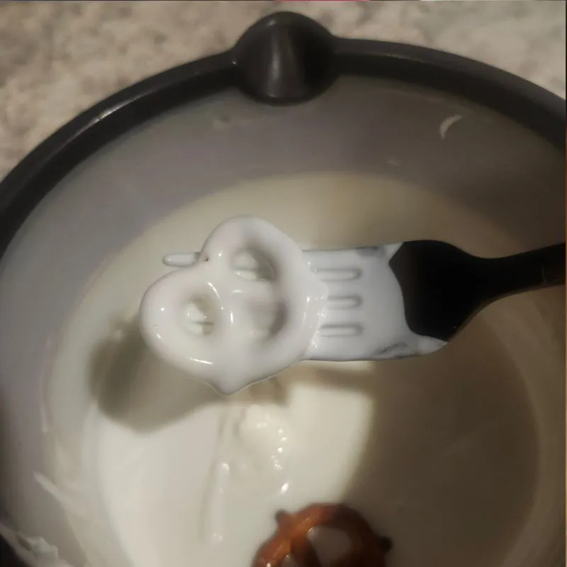 dipping pretzel in melted almond bark
