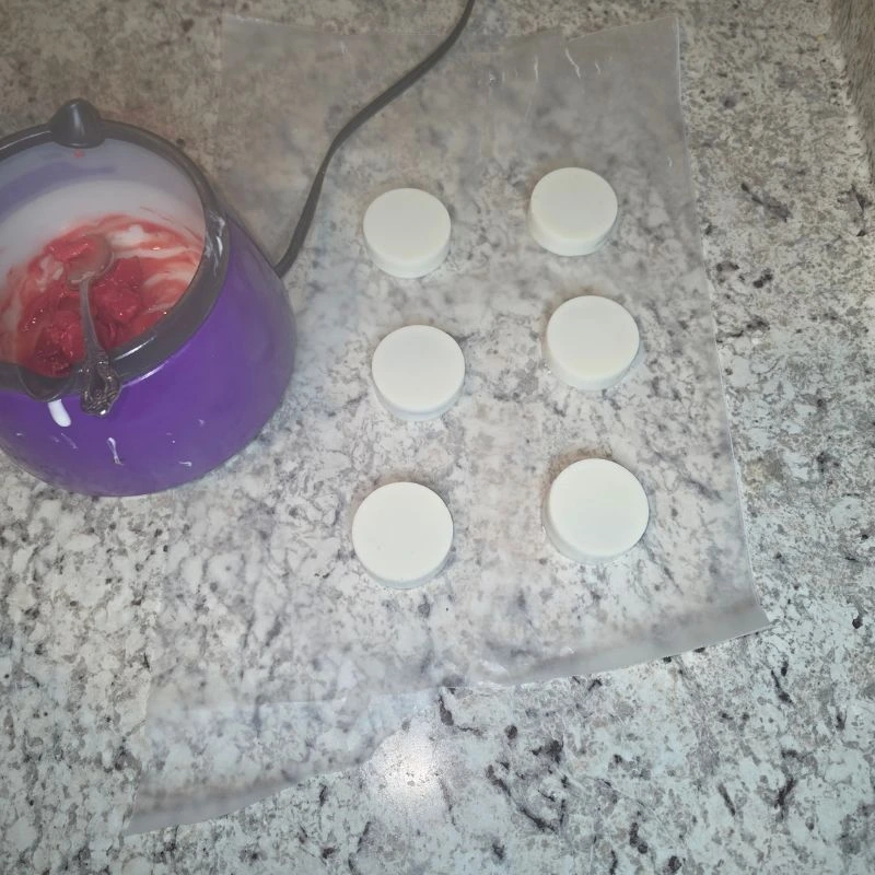 oreo cookies covered in almond bark on parchment paper with red candy melts in melting pot