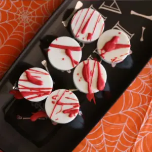 Blood Splattered Chocolate Covered Oreos (Easy Halloween Treat) on black tray sitting on orange spider web table cloth