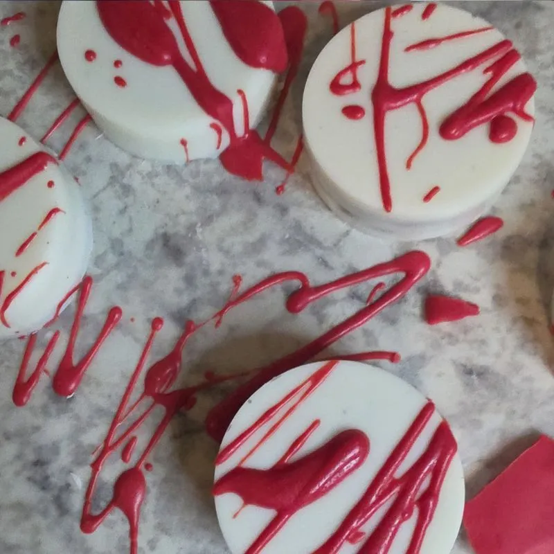 oreo cookies covered in white almond bark with red candy melts providing a blood splattered look