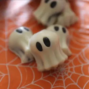 Easy No Bake Halloween Ghost Oreo Balls 17 Oreo ball halloween ghosts on orange table cloth with spider webss.