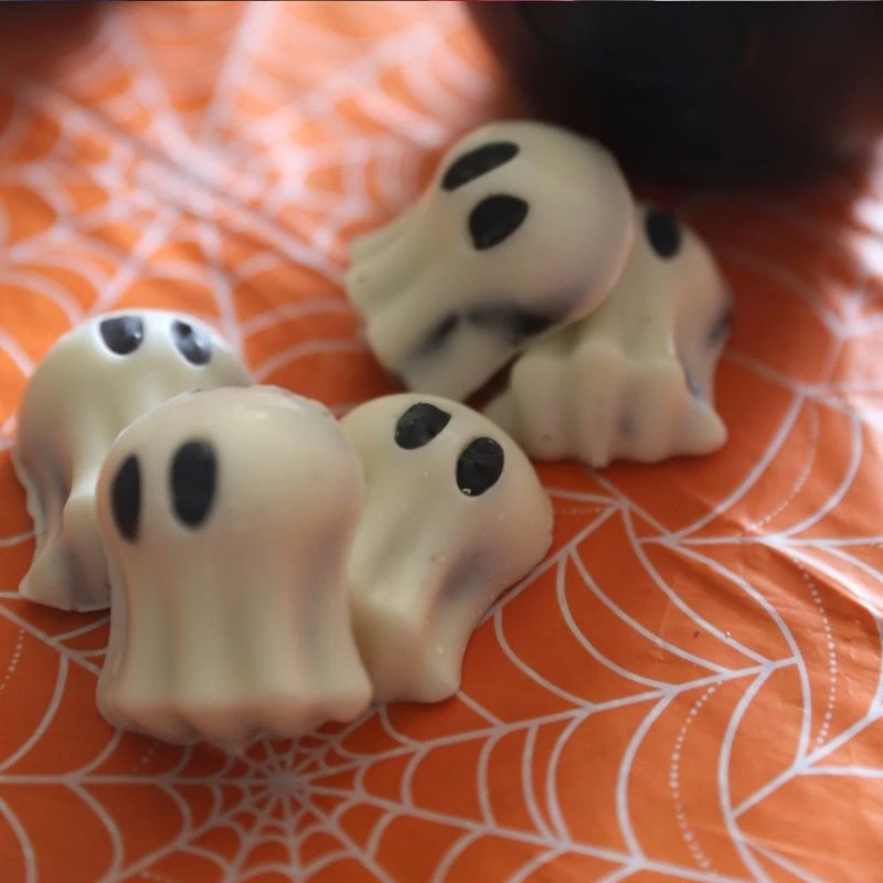 Easy No Bake Halloween Ghost Oreo Balls 6 Ghost Oreo Balls layed out on a orange table cloth with spider webs
