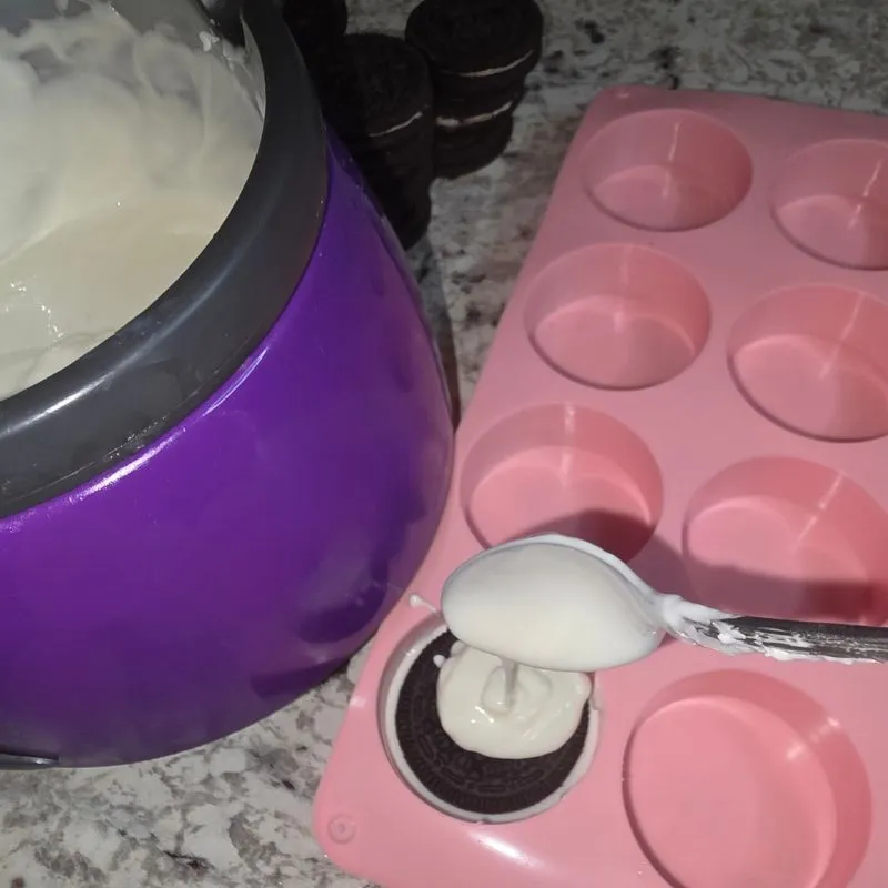 covering oreo cookie in mold with white almond bark to make mummy cookies