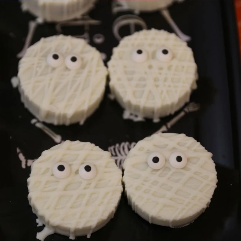 Easy Mummy Halloween Chocolate Covered Oreos on a black plate