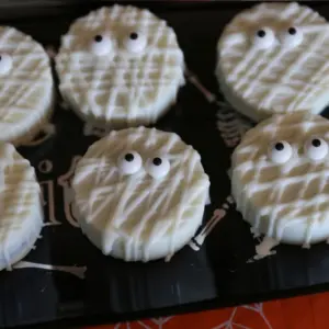 Easy Mummy Oreos (Halloween Chocolate Covered Oreos) laying on a black platter