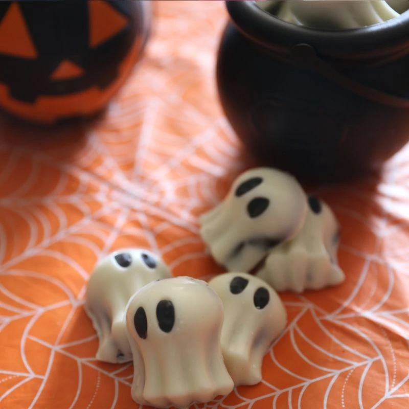 Easy No Bake Halloween Ghost Oreo Balls 18 Ghost Oreo Balls layed out on a orange table cloth with spider webs